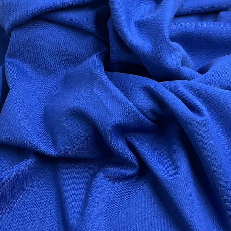 A close-up of draped royal blue fabric with soft folds and a smooth texture.