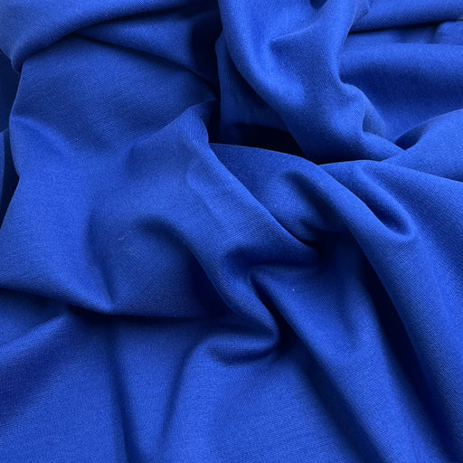 A close-up of draped royal blue fabric with soft folds and a smooth texture.