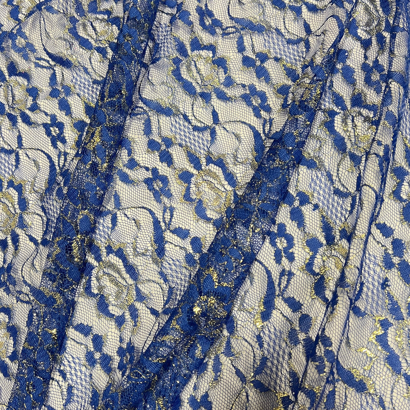 A close-up of a royal blue floral lace fabric with gold glitter accents over a white mesh background.