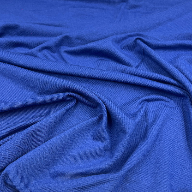 A close-up of draped royal blue fabric with soft folds and a smooth texture.