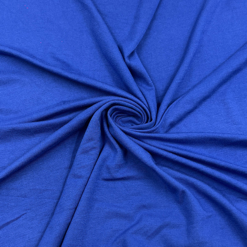 A close-up of bright royal blue fabric arranged in a spiral drape, showing the material texture and folds.