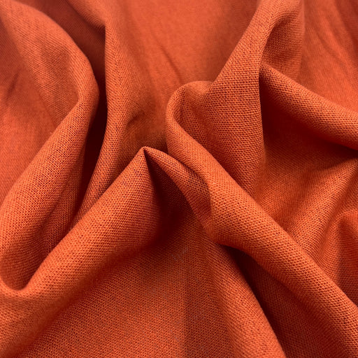 Rust orange laundered linen bunched to show off silky smooth drape