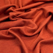 Rust orange rayon lycra jersey shown up close to display fine knit and soft hand.