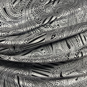 A close-up of draped fabric with an intricate black and silver paisley and abstract line pattern.