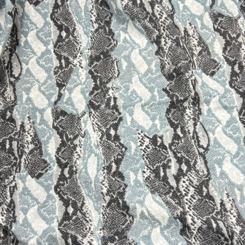 A close-up of a fabric pattern featuring vertical wavy stripes in black and gray snakeskin print over a light blue-gray background.