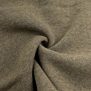 A close-up of textured knit fabric in a muted taupe-brown color, shown with soft folds and a twisted center to highlight the material's drape and weave.