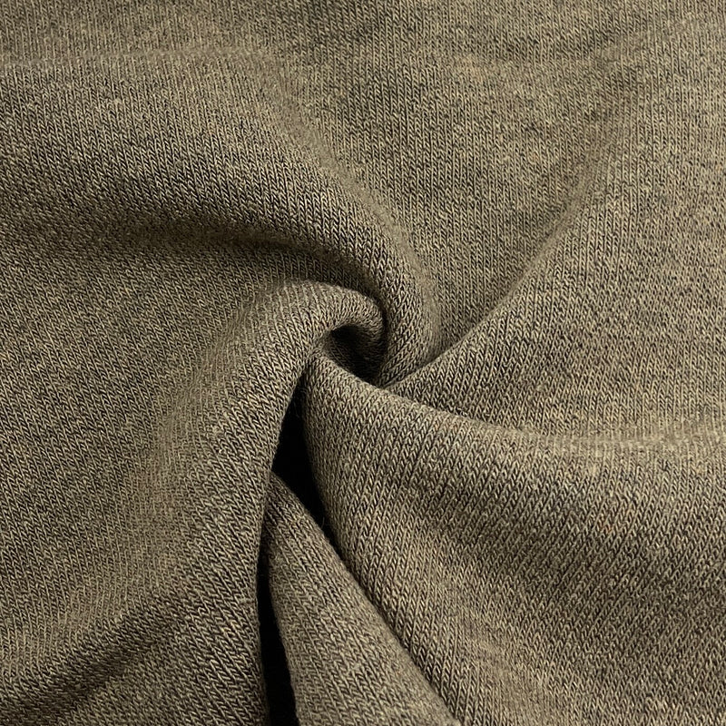 A close-up of textured knit fabric in a muted taupe-brown color, shown with soft folds and a twisted center to highlight the material's drape and weave.