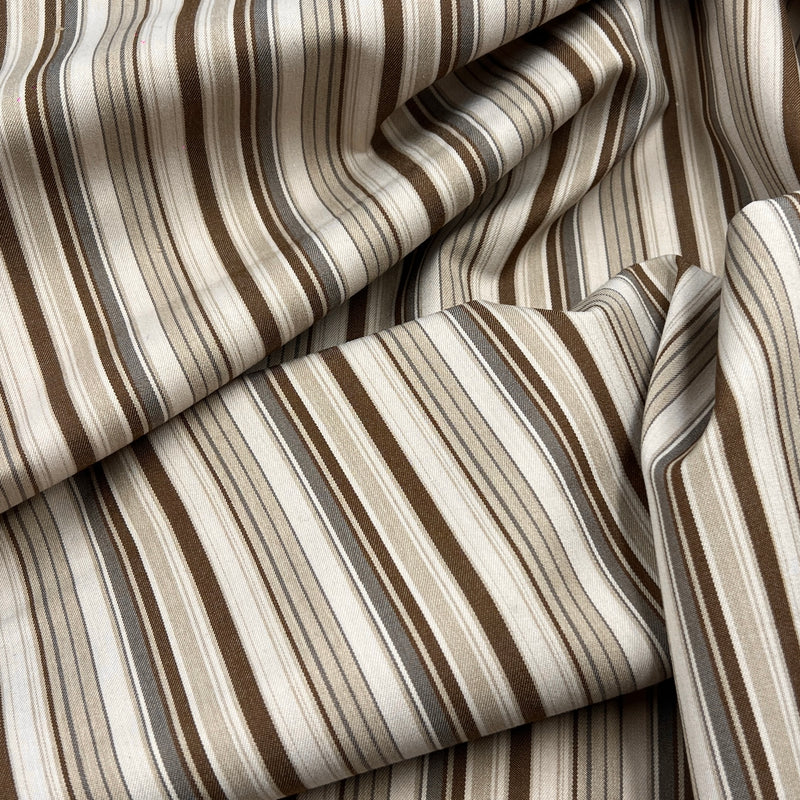 A close-up of draped striped fabric with vertical bands in beige, cream, brown, taupe, and gray.