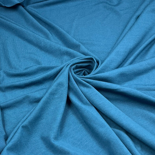A close-up of draped blue fabric with a central swirl, showing the material's texture and color.