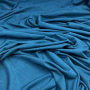 A close-up of draped blue fabric with soft folds and a smooth texture filling the frame.