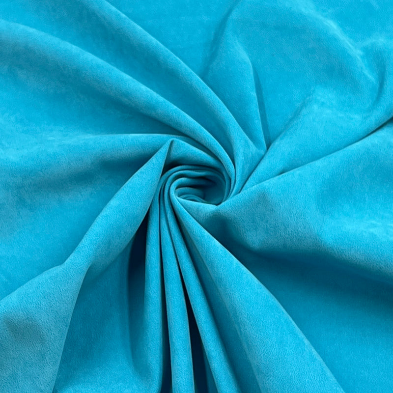 A close-up of bright turquoise blue fabric arranged in a spiral drape, showing the material texture and color.