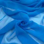 A close-up of draped sheer blue fabric with soft folds and a light blue satin-like underside.