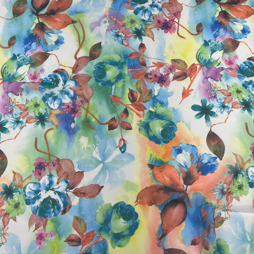 A close-up of a watercolor-style floral print with blue, green, purple, pink, and brown flowers and leaves on a light background.