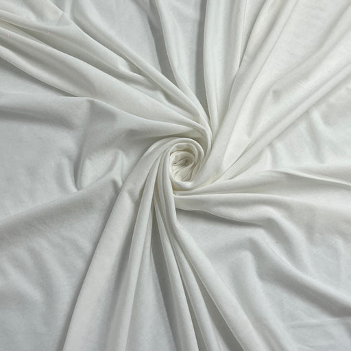 White fabric draped in a spiral pattern, showing its soft texture and drape.