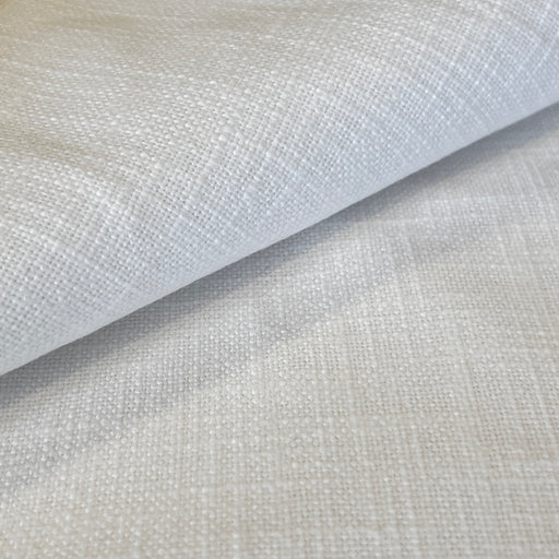 A close-up of a light beige woven fabric with a textured linen-like pattern, shown with a folded corner revealing the material's depth and color.