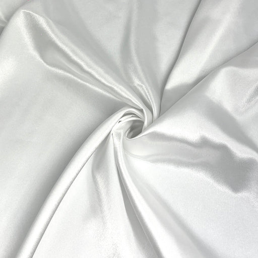 A close-up of draped white satin fabric with a central swirl, showing its smooth texture and soft sheen.