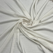 A close-up of light cream or off-white fabric arranged in a spiral drape, showing the material texture and soft folds.