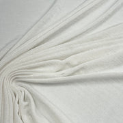 A close-up of draped off-white fabric with a soft, slightly textured surface, arranged in elegant folds radiating from the center.