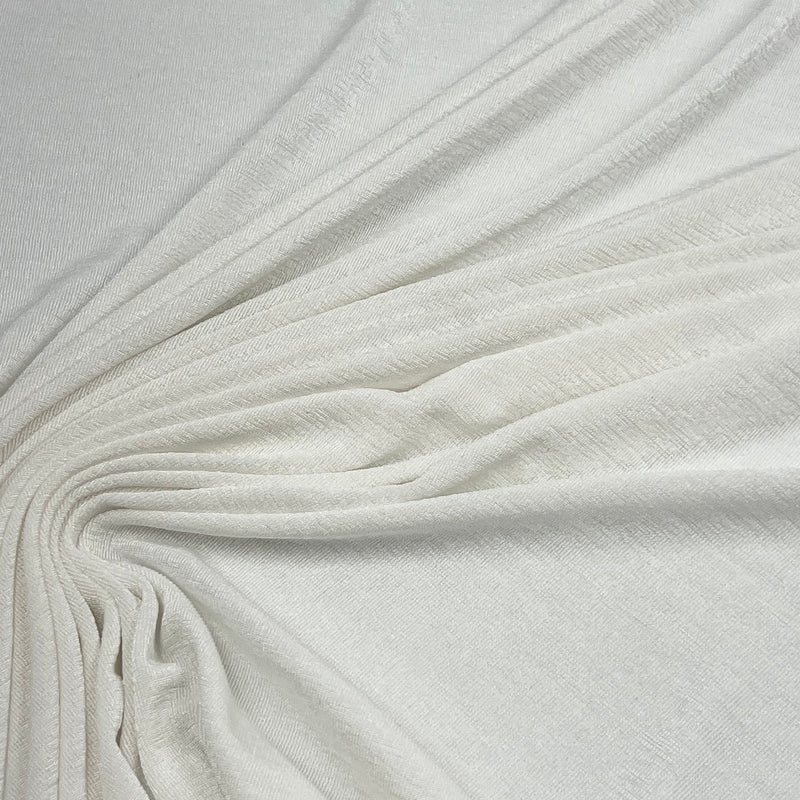 A close-up of draped off-white fabric with a soft, slightly textured surface, arranged in elegant folds radiating from the center.