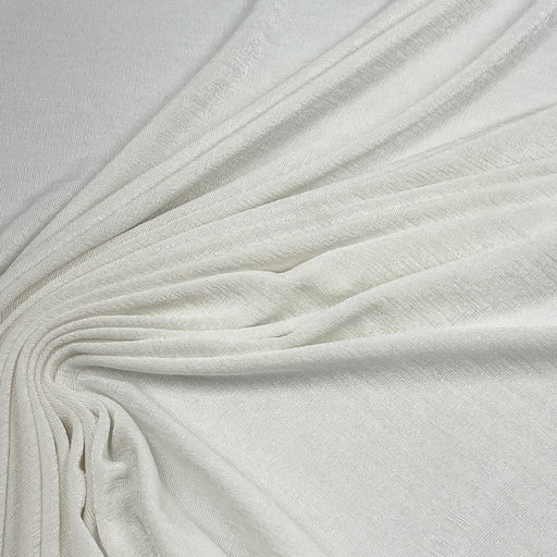 A close-up of draped off-white fabric with a soft, slightly textured surface, arranged in elegant folds radiating from the center.