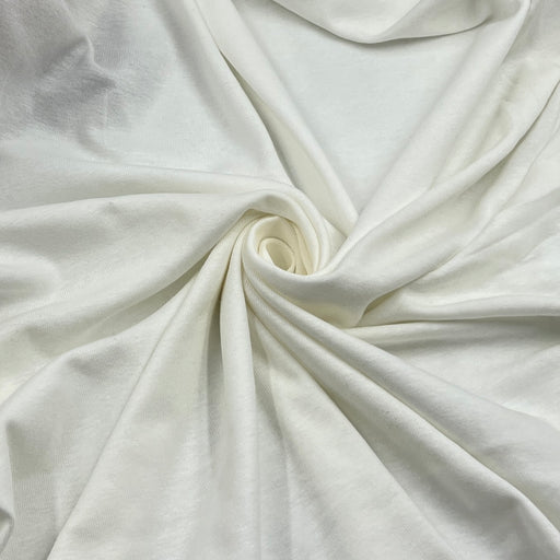 A close-up of draped off-white fabric arranged in a spiral, showing its soft texture and light color.
