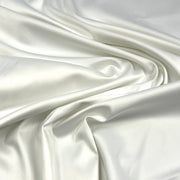 White satin fabric draped in soft folds, showing a smooth, lustrous texture with a subtle sheen.