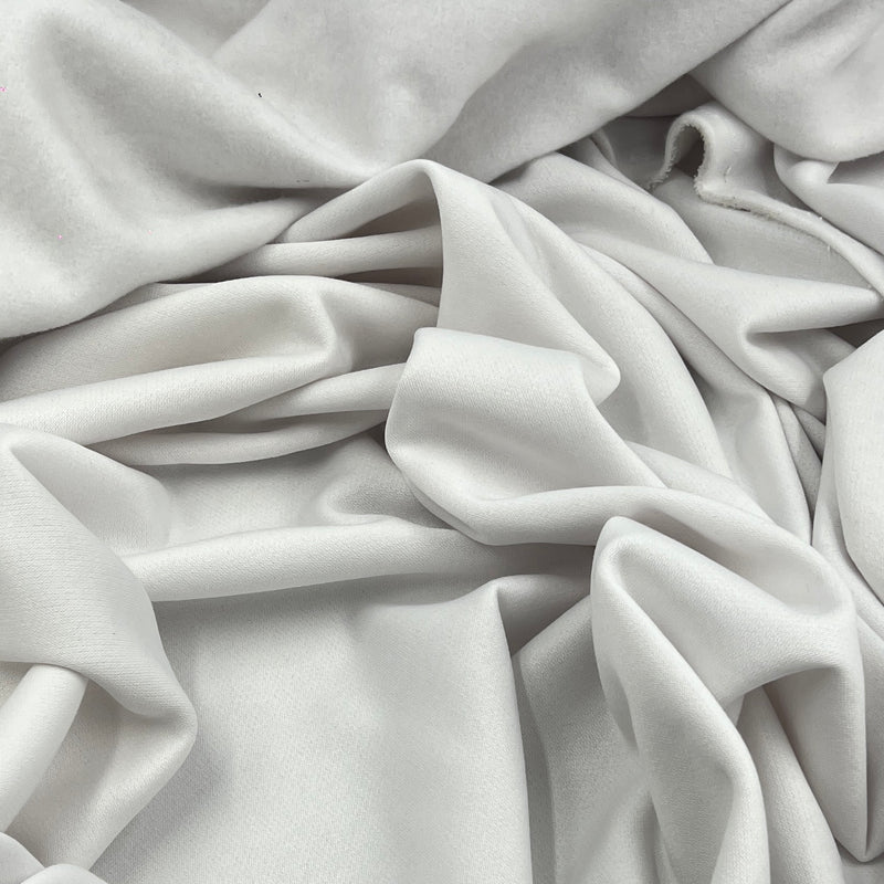 A close-up of draped white fabric with soft folds and a smooth texture filling the frame.
