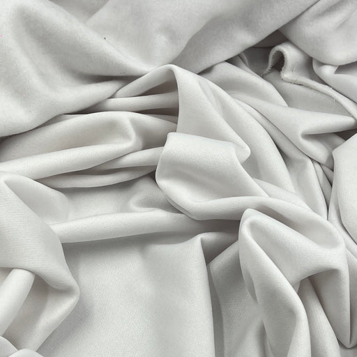 A close-up of draped white fabric with soft folds and a smooth texture filling the frame.