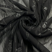 Black sheer fabric with silver floral glitter design and metallic stripes, arranged in a spiral drape.