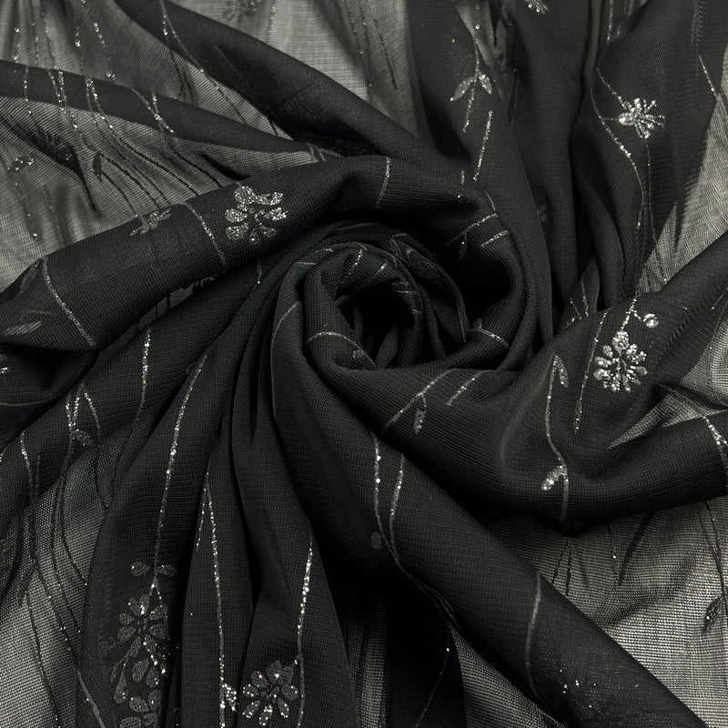 Black sheer fabric with silver floral glitter design and metallic stripes, arranged in a spiral drape.