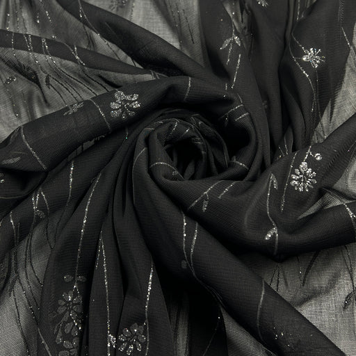 Black sheer fabric with silver floral glitter design and metallic stripes, arranged in a spiral drape.
