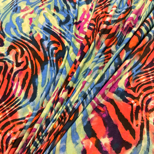 A close-up of a draped fabric with a vibrant, multicolored abstract print featuring zebra-like stripes in orange, red, blue, yellow, black, and pink.