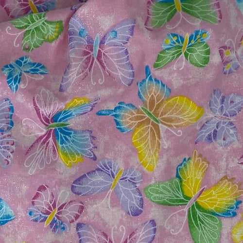 Close-up of pink fabric with a metallic print of butterflies in various colors including blue, green, and yellow.